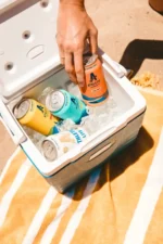 Cooler filled with cans of Athletic Brewing Co.'s non-alcoholic beers on a sunny day, perfect for outdoor adventures and refreshing moments.