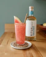 Watermelon cocktail with Ritual Zero Proof tequila alternative bottle in the background.