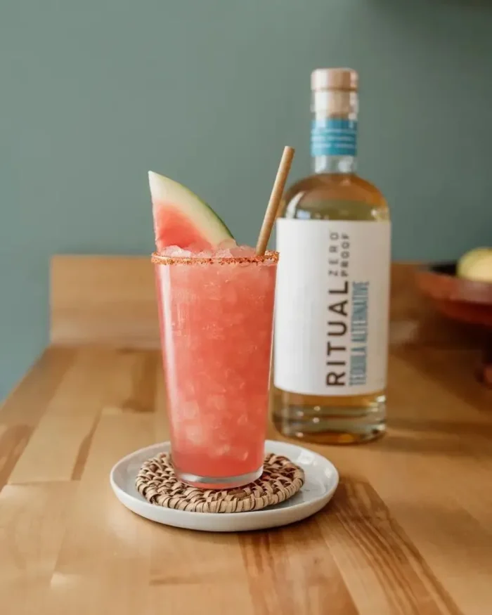 Watermelon cocktail with Ritual Zero Proof tequila alternative bottle in the background.