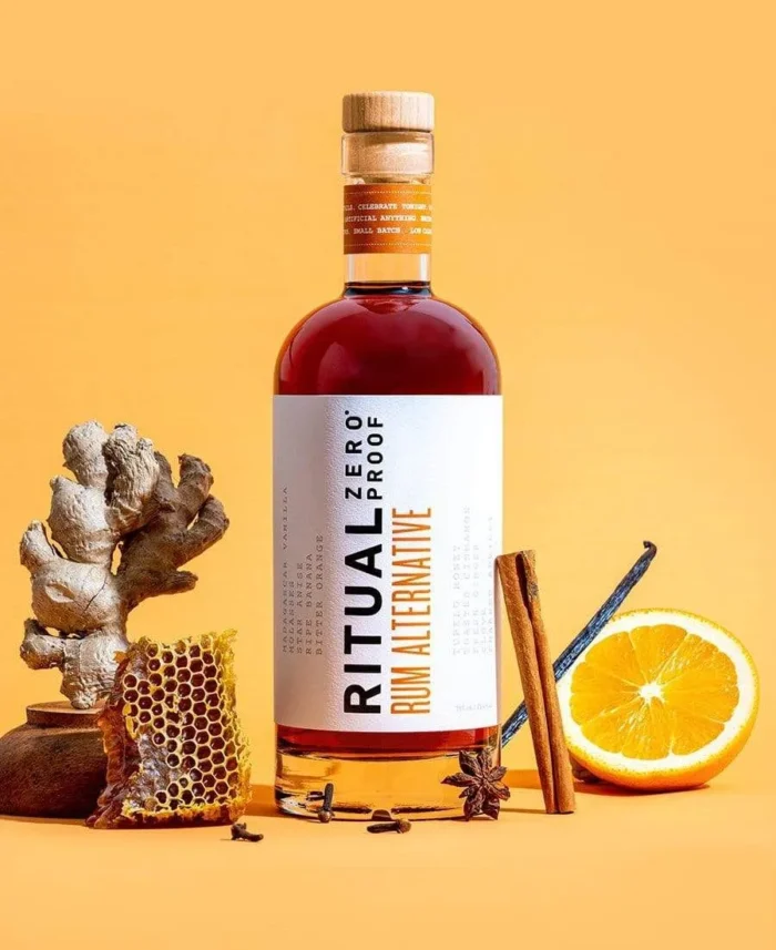 Ritual Zero Proof Rum Alternative surrounded by natural ingredients like orange, honeycomb, and spices.