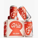 Ghia Ginger cans and packaging featuring bold red and white branding, with non-alcoholic aperitif label.