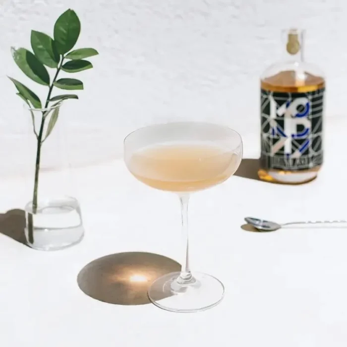 Elegant cocktail with Monday whiskey bottle on a minimalistic table setting.