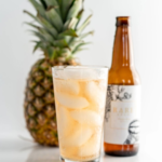 Rare Brew pineapple drink served in a chilled glass with fresh pineapple in the background.