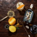 Monday Zero Alcohol Whiskey bottle with a crafted cocktail, citrus garnish, and bar tools on a wooden table.