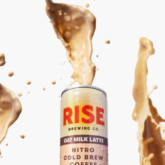 Rise Nitro Cold Brew Oat Milk Latte can with splashes of creamy coffee against a white background.