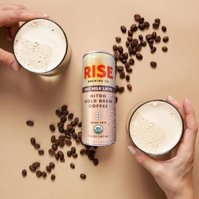 Rise Nitro Cold Brew Oat Milk Latte can with splashes of creamy coffee against a white background.