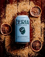 Ceria Brewing Grainwave can surrounded by grains and dried citrus, showcasing non-alcoholic craft beer.