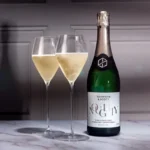 Elegant bottle of sparkling wine with two filled glasses on a marble countertop.