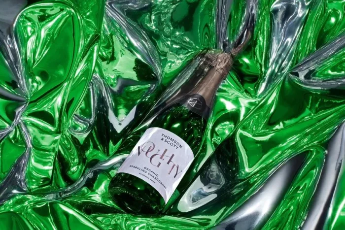 Sparkling wine bottle displayed on vibrant green reflective fabric, exuding luxury and style.