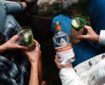 Wilderton non-alcoholic spirit bottle and mojito-style cocktails enjoyed outdoors with friends.