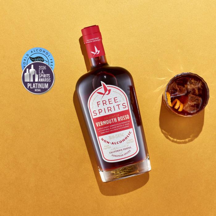 Free Spirits Vermouth Rosso non-alcoholic bottle with award badge and an orange-garnished cocktail on a golden background.