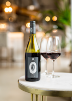 Bottle of premium red wine with two glasses on a white table, set in a modern, elegant ambiance.