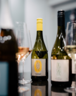 Selection of wine bottles with glasses, showcasing a variety of wines in an elegant indoor setting.