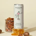 Treehouse Naturals Original Pecanmilk can displayed with a jar of pecans, honeycomb, and whole pecans on a beige background.