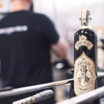 The Blind Tiger non-alcoholic spirit bottle with vintage-style label displayed in an industrial setting.