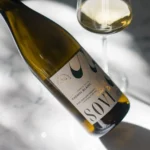 Elegant Sovi Chenin Blanc bottle displayed on a sunlit marble surface with a filled glass nearby.