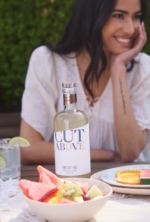 Cut Above Mezcal bottle with a joyful summer setting, fresh fruits, and a relaxed atmosphere.